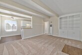Located at 363 Palm Avenue in Imperial Beach, CA, this single-story, 2-bedroom, 1-bathroom home offers a well-organized layout across a compact but functional floor plan. A defining architectural feature throughout the home is the white-painted tongue-and-groove ceiling with exposed structural beams, lending a mid-century character to each room.

The living room is bright and open, featuring wall-to-wall carpet, a ceiling fan, and a set of built-in shelving units flanking the front entry door. A half-wall with a countertop pass-through connects the living area to the kitchen, creating an open, cohesive feel. The galley-style kitchen is appointed with white cabinetry, granite-toned countertops, a double-basin sink, and stainless steel appliances including a gas range and refrigerator, all set atop warm hardwood-style flooring.

Both bedrooms are carpeted and feature beamed ceilings, vertical blinds allowing natural light, and mirrored sliding closet doors that add depth to each room. The bathroom includes a single-vanity with warm wood cabinetry, a tiled tub-shower combination, a small window for ventilation, and hardwood-style flooring.

The home's consistent design details and neutral palette create a cohesive and practical living environment in the coastal community of Imperial Beach.