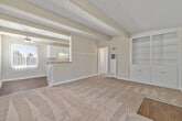Located at 363 Palm Avenue in Imperial Beach, CA, this single-story, 2-bedroom, 1-bathroom home offers a well-organized layout across a compact but functional floor plan. A defining architectural feature throughout the home is the white-painted tongue-and-groove ceiling with exposed structural beams, lending a mid-century character to each room.

The living room is bright and open, featuring wall-to-wall carpet, a ceiling fan, and a set of built-in shelving units flanking the front entry door. A half-wall with a countertop pass-through connects the living area to the kitchen, creating an open, cohesive feel. The galley-style kitchen is appointed with white cabinetry, granite-toned countertops, a double-basin sink, and stainless steel appliances including a gas range and refrigerator, all set atop warm hardwood-style flooring.

Both bedrooms are carpeted and feature beamed ceilings, vertical blinds allowing natural light, and mirrored sliding closet doors that add depth to each room. The bathroom includes a single-vanity with warm wood cabinetry, a tiled tub-shower combination, a small window for ventilation, and hardwood-style flooring.

The home's consistent design details and neutral palette create a cohesive and practical living environment in the coastal community of Imperial Beach.
