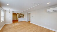 This 2-bedroom, 1-bathroom residence at 200 Broadway in Troy, NY offers a thoughtfully designed single-floor layout with a clean, contemporary aesthetic. The open-concept living and dining area is anchored by light hardwood flooring, recessed lighting, and a wall-mounted mini-split system, with multiple windows fitted with blinds that invite ample natural light. The kitchen seamlessly connects to the living space and features white shaker-style cabinetry, a light quartz countertop, stainless steel appliances including a range, microwave, dishwasher, and refrigerator, plus pendant lighting above a peninsula breakfast bar. Both bedrooms are carpeted in warm neutral tones and include closets, track lighting, and windows that bring in natural light. The primary bedroom benefits from a wall-mounted mini-split unit for climate control. The shared full bathroom is well-appointed with large-format tile flooring, a spacious white vanity with dual sinks, a wide mirror with globe lighting, and accessibility grab bars. A connecting hallway ties the layout together, providing smooth circulation throughout. The overall palette of soft whites and warm beiges creates a bright, cohesive ambiance across the entire residence.