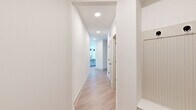 This well-appointed single-story home offers two bedrooms and two bathrooms within a thoughtfully designed, modern layout. Light wood-tone flooring runs throughout, creating a cohesive and airy feel across every room.

The kitchen serves as the heart of the home, showcasing a large center island with a white quartz countertop, a deep single-basin sink with a matte black faucet, and striking pendant lighting overhead. Gray shaker-style cabinetry, a herringbone tile backsplash, and stainless steel appliances — including a French door refrigerator and gas range — complete the space. A built-in desk area with open shelving adds a practical touch.

The hallways are bright and clean with recessed lighting, guiding residents to the private quarters. The primary bedroom is generously proportioned, featuring dual windows that invite natural light and an outdoor view, complemented by a ceiling fan. A dedicated walk-in closet offers ample organized storage with built-in shelving and dual clothing rods.

The bathrooms are finished with crisp white cabinetry, quartz countertops, matte black hardware, and a marble-style tiled tub surround. A dedicated laundry room houses a full-size washer and dryer with overhead shelving for added convenience. The second bedroom is equally bright and well-sized, with easy access to the main living areas.