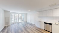 Located at 2376 Dundas Street West in Toronto's Junction neighbourhood, Unit 613 is a well-designed two-bedroom, two-bathroom suite that makes efficient use of its single-level layout. Light wood laminate flooring runs throughout, lending a clean, cohesive look to every room.

The open-concept kitchen and living area forms the heart of the unit. The kitchen is outfitted with sleek white cabinetry extending to the ceiling, a white subway tile backsplash, stainless steel appliances including a refrigerator, stove, microwave, and dishwasher, and a track lighting fixture overhead. The adjoining living area benefits from large floor-to-ceiling windows and sliding glass doors that open to a balcony, flooding the space with natural light and offering views of the surrounding Toronto streetscape.

Both bedrooms feature the same light wood flooring and crisp white walls, with the second bedroom offering a large window with city views. Each of the two bathrooms includes a soaker tub-shower combination finished with large-format grey tile surrounds and chrome fixtures, presenting a clean, contemporary aesthetic throughout. A dedicated closet adds practical storage to this well-appointed urban suite.