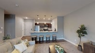 This single-floor residence offers a thoughtfully designed open-concept layout that seamlessly connects the living and kitchen areas. The kitchen is a standout feature, equipped with rich dark-wood cabinetry, stainless steel appliances including a refrigerator, microwave, and range, and expansive granite countertops. A large peninsula with seating for several barstools serves as both a casual dining space and a natural divider between the kitchen and living area. Pendant lighting above the peninsula adds a refined touch, while recessed lighting brightens the entire kitchen.

The living area is carpeted and bathed in natural light from a sliding glass door, which also provides outdoor access. A ceiling fan overhead adds comfort, and the neutral gray walls create a calm, cohesive ambiance throughout the space.

The bedroom is generously sized with plush carpeting, a ceiling fan, and a well-organized closet with bifold doors offering ample storage. The bathroom features dark-wood vanity cabinetry with granite countertops, a tub-shower combination, and wood-look flooring. A practical stacked washer and dryer unit is conveniently integrated within the bathroom space. Throughout the residence, consistent use of neutral tones, quality finishes, and functional design create a comfortable and modern living environment.