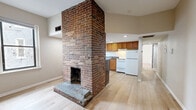 Located at 3507 Cable Pl in Pittsburgh, PA, this two-bedroom, one-bathroom unit offers a well-organized single-floor layout that balances classic character with everyday functionality. The living room serves as the heart of the home, anchored by a striking exposed brick fireplace that adds warmth and historic charm to the space. Light-toned hardwood-style flooring runs throughout the living area, complementing the neutral walls and creating a clean, inviting atmosphere. Natural light filters in through windows that frame views of the surrounding neighborhood. The kitchen is thoughtfully equipped with warm oak cabinetry extending to the ceiling for generous storage, dark granite-style countertops, a double-basin stainless steel sink, and white appliances including a gas range and refrigerator. A peninsula counter provides additional prep space and connects the kitchen to the living area. Both bedrooms feature soft wall-to-wall carpeting and individual windows that bring in natural light, with the primary bedroom offering a comfortable, well-proportioned layout. The bathroom includes a full-size soaking tub and shower combination with built-in shelving. Throughout the unit, the blend of exposed brick, light flooring, and neutral tones creates a cohesive and practical living environment.