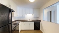 This single-floor residence offers two bedrooms and one and a half bathrooms within a thoughtfully designed layout. The kitchen is a standout feature, showcasing white shaker-style cabinetry that extends to the ceiling for ample storage, complemented by dark granite-look countertops and a classic white subway tile backsplash. A stainless steel sink, electric range, and black dishwasher complete the kitchen's functional setup, while warm hardwood-style flooring ties the space together. The under-cabinet lighting and flush ceiling fixture provide bright, even illumination throughout the kitchen. A pass-through window connects the kitchen to an adjacent area, enhancing the open feel of the home. The clean, neutral color palette of white walls and trim creates a bright and airy atmosphere throughout the residence, offering a versatile backdrop for a variety of interior styles. With its efficient use of space and updated finishes, this home delivers a comfortable and practical living environment suited for a range of lifestyles.