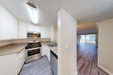 This single-floor residence offers a thoughtfully designed layout that balances functionality and comfort throughout. The kitchen is fully equipped with stainless steel appliances, including a gas range, over-the-range microwave, and dishwasher, all complemented by crisp white cabinetry, granite-style countertops, and durable light-tone wood flooring. A pass-through counter connects the kitchen to the adjoining living and dining area, creating an open and connected feel.

The living area is a standout space, featuring crown molding, a tiled fireplace, and a sliding glass door that opens to a private balcony, allowing for natural light and outdoor views. The flooring transitions to a rich, deeper-toned hardwood, adding warmth to the room.

The bedroom is a comfortable, well-lit space with a large window that lets in natural light, finished with light wood-tone flooring and neutral walls. A hallway connects the bedroom to a closet and additional storage, with a textured ceiling consistent throughout the unit.

The bathroom features a clean, minimalist design with a quartz-style countertop, undermount sink, brushed nickel fixtures, and large mirrors that enhance the sense of space. Overall, the residence presents a move-in-ready interior with consistent, modern finishes throughout.