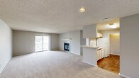 Located at 125 Royal Dr in Madison, Alabama, this single-floor, 2-bedroom, 2-bathroom home offers a functional and comfortable layout. The open living room is generously sized, featuring neutral-toned carpet, a textured ceiling, and a sliding glass door that floods the space with natural light and provides access to an outdoor balcony. A fireplace adds a cozy focal point to the living area. The kitchen is laid out in a galley style with white cabinetry accented by wood trim, white appliances including a range and refrigerator, a double-basin sink, and durable hardwood-style flooring — connected to the living area via a pass-through counter. The spacious primary bedroom includes a ceiling fan with light fixture and a window for natural light, with plush carpet underfoot. A hallway leads to both bedrooms and the closet, maintaining a clear and organized flow throughout. Both bathrooms are clean and practical, each featuring a tub-shower combination, vanity with storage, and a large mirror. The secondary bathroom includes a well-lit vanity with wood-trimmed cabinetry and hardwood-style flooring. Overall, the home presents a straightforward, move-in-ready layout suitable for comfortable everyday living in a residential Madison neighborhood.