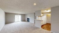 Located at 125 Royal Dr in Madison, Alabama, this single-floor, 2-bedroom, 2-bathroom home offers a functional and comfortable layout. The open living room is generously sized, featuring neutral-toned carpet, a textured ceiling, and a sliding glass door that floods the space with natural light and provides access to an outdoor balcony. A fireplace adds a cozy focal point to the living area. The kitchen is laid out in a galley style with white cabinetry accented by wood trim, white appliances including a range and refrigerator, a double-basin sink, and durable hardwood-style flooring — connected to the living area via a pass-through counter. The spacious primary bedroom includes a ceiling fan with light fixture and a window for natural light, with plush carpet underfoot. A hallway leads to both bedrooms and the closet, maintaining a clear and organized flow throughout. Both bathrooms are clean and practical, each featuring a tub-shower combination, vanity with storage, and a large mirror. The secondary bathroom includes a well-lit vanity with wood-trimmed cabinetry and hardwood-style flooring. Overall, the home presents a straightforward, move-in-ready layout suitable for comfortable everyday living in a residential Madison neighborhood.