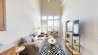 This thoughtfully designed two-story residence offers 2 bedrooms and 2 bathrooms across two balanced floors of living space. The ground floor immediately impresses with dramatically high ceilings that amplify the sense of openness, anchored by a striking exposed concrete column that serves as a defining architectural element. Polished concrete floors run throughout, complementing the industrial-modern aesthetic. Large, multi-pane windows flood the living area with natural light and frame outdoor views, while a ceiling fan overhead adds practical comfort. A dedicated nook accommodates a dining area alongside the open living space. The kitchen is well-equipped with warm wood cabinetry, granite countertops, a white subway tile backsplash, and stainless steel appliances. The second floor houses the bedrooms, including a cozy primary bedroom with hardwood-style flooring and a low horizontal window that draws in soft, natural light. The second bedroom benefits from a large window with outdoor views and a signature exposed concrete column detail. Both bathrooms feature wood vanities with granite countertops and polished concrete floors. A dedicated in-unit laundry room with full-size washer and dryer adds everyday convenience, rounding out this architecturally distinctive and functional home.