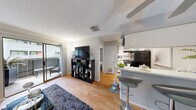This compact yet efficiently designed one-bedroom, one-bathroom unit offers a thoughtful layout that maximizes every square foot across a single floor. Hardwood-style flooring flows consistently throughout, lending warmth and visual continuity to the space.

The living room serves as the heart of the unit, featuring a textured ceiling, a ceiling fan, and a sliding glass door that opens to a private balcony — allowing natural light to fill the room and providing a comfortable outdoor seating area. The open sightlines connect the living area seamlessly to the kitchen.

The kitchen is equipped with black appliances, including a full-size refrigerator and electric range, complemented by a mosaic tile backsplash, white cabinetry, and light countertops. A peninsula with bar seating creates a natural divide between the kitchen and living space, adding a functional dining option.

The bedroom is a comfortable retreat with a ceiling fan, a window with natural light, closet storage, and a neutral color palette that creates a calm atmosphere. The bathroom features a combined tub and shower with a curtain enclosure, white cabinetry, and a vanity with ample counter space. Overall, the unit presents a clean, modern, and functional living environment.