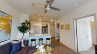 This single-floor residence offers a thoughtfully designed open-concept layout that seamlessly connects the living and kitchen areas. The kitchen is a standout feature, showcasing dark espresso cabinetry with sleek hardware, light granite countertops, a classic white subway tile backsplash, and a full suite of stainless steel appliances including a range, microwave, dishwasher, and refrigerator. A peninsula with an undermount sink and pendant lighting provides additional prep space and doubles as a casual dining area with stylish bar seating.

The living area flows naturally from the kitchen, highlighted by wood-look plank flooring, a ceiling fan, and neutral walls that create a bright, welcoming atmosphere. The primary bedroom features plush carpeting, access to a private en-suite bathroom, and connects to an additional room, offering flexible use of space. The bathroom is equipped with wood-look flooring, a walk-in glass-enclosed shower, and dark vanity cabinetry. A secondary bedroom benefits from a large window that allows ample natural light and outdoor views. Throughout the unit, clean lines and contemporary finishes create a cohesive, modern aesthetic.