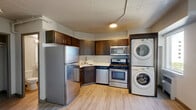Located at 707 W Fifth Ave in Spokane, Washington, this efficiently designed studio unit offers a well-organized, single-floor layout that makes the most of its compact footprint. Light wood-style flooring runs throughout the space, lending a clean, modern aesthetic and visual continuity between areas.

The kitchen is a standout feature, equipped with a full suite of stainless steel appliances including a gas range with oven, over-the-range microwave, dishwasher, and a full-size refrigerator. Rich dark-toned cabinetry provides ample storage, while light countertops create a pleasing contrast. Conveniently positioned adjacent to the kitchen is a stacked in-unit washer and dryer, offering a practical amenity within the home.

The open living area is bright and airy, benefiting from natural light through windows that overlook the surrounding neighborhood. The neutral white walls and clean lines keep the space feeling open and versatile. A dedicated closet offers organized storage, and a utility panel is accessible near the entryway.

The bathroom is clean and functional, featuring a full tub/shower combination with built-in shelving, a pedestal sink, and wood-style flooring that complements the rest of the unit. The overall ambiance of this unit is modern and low-maintenance, well-suited for urban living in Spokane.