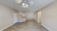 Located at 2931 Barker Cypress Rd in Houston, TX 77084, this single-floor unit offers a clean, functional layout with a neutral color palette and consistent wood-look plank flooring throughout. The open living area is bright and spacious, featuring a ceiling fan with integrated lighting, smooth walls with classic white baseboards, and a pass-through counter that connects to the kitchen — ideal for an open-concept feel. Natural light filters in through blinds-fitted windows and glass panel doors, offering views of the surrounding greenery. The kitchen is well-equipped with light maple cabinetry, laminate countertops, a stainless steel sink, and black appliances including a dishwasher, range, and over-the-range microwave, all set on tile flooring. A dedicated bedroom features its own ceiling fan, a large window with an outdoor view, and the same wood-look flooring found throughout. The bathroom includes wood-look tile flooring, a wall-mounted cabinet for storage, and a recessed access panel. The space is practical and move-in ready, with a textured ceiling in select areas, recessed ventilation, and a straightforward, well-maintained interior suitable for comfortable everyday living.