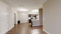 This single-floor residence offers a thoughtfully designed open-concept layout that seamlessly connects the living area and kitchen, creating a bright and cohesive living environment. Rich hardwood-style flooring extends throughout the main living spaces, complemented by warm neutral-toned walls that lend the interior a clean, modern aesthetic.

The kitchen is a standout feature, equipped with dark espresso-stained cabinetry, sleek white countertops, and a full suite of stainless steel appliances including a gas range, microwave, and refrigerator. A peninsula with pendant lighting defines the kitchen's boundary with the living area, while a dedicated dining space is accented by an elegant chandelier overhead. A subway tile backsplash adds a refined finishing touch to the kitchen's design.

The bathroom is well-appointed with a full tub-shower combination, a dark-cabinetry vanity with a white countertop, a large mirror, and hardwood-style flooring that ties it cohesively to the rest of the unit.

The bedroom offers plush carpeting for comfort, a ceiling fan, a bright window that invites natural light, and access to a walk-in closet, providing generous storage. Overall, the space combines functional design with modern finishes for a comfortable and stylish living experience.