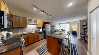 Located at 101 10th St E in Saint Paul, MN, this one-bedroom, one-bathroom unit offers a well-designed open-concept layout across a single floor. The kitchen is a standout feature, equipped with warm wood cabinetry, dark granite countertops, a full suite of stainless steel appliances including a refrigerator, dishwasher, and range, a tile backsplash, and a large island with bar seating — ideal for both cooking and casual dining. Track lighting overhead adds a modern, functional touch. The kitchen flows seamlessly into the living area, which is anchored by large floor-to-ceiling sliding glass doors that open to a private balcony, flooding the space with natural light and offering views of the surrounding urban streetscape. Hardwood-style flooring runs throughout the main living areas, adding warmth and cohesion. The bedroom is a comfortable retreat with carpet flooring, a ceiling fan, and a well-sized window that brings in additional natural light. The bathroom features tile flooring, a soaking tub with shower, a warm wood vanity with an undermount sink, and decorative round mirrors. A dedicated closet provides convenient storage. The overall ambiance is modern and urban, with clean finishes and a practical, livable design.