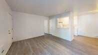Located at 100 Larissa Ln in Vallejo, California, this two-bedroom, three-bathroom residence offers a thoughtfully laid-out single-floor plan. Light gray luxury vinyl plank flooring runs consistently throughout, creating a cohesive and modern aesthetic. The combined living, dining, and kitchen area forms the heart of the home, with a ceiling fan overhead and a sliding glass door leading to a private balcony that brings in natural light. The kitchen is designed in a galley style, featuring white cabinetry, stone-look countertops, a full suite of white appliances including an electric range and refrigerator, and an overhead range hood. A pass-through window connects the kitchen to the living and dining area, enhancing the open feel of the space. The primary bedroom is a well-proportioned retreat with direct access to an en-suite bathroom complete with white vanity cabinetry and a full mirror. The second bedroom also benefits from natural light through vertical-blind-fitted windows and baseboard heating. Three full bathrooms serve the residence, each featuring clean white fixtures including tub-shower combinations. Five closets distributed throughout provide generous storage. A hallway connects the bedrooms and bathrooms efficiently. The overall palette of crisp whites and neutral tones lends the space a clean, move-in-ready ambiance.