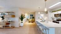 Located in Cocoa, Florida, this single-story 2-bedroom, 3-bathroom home offers a well-designed layout with comfortable living spaces throughout. The open-concept kitchen and living area serves as the heart of the home, featuring white shaker cabinetry, a subway tile backsplash, stainless steel appliances, and a large central island with bar seating — all illuminated by pendant lighting and a skylight. The living room flows seamlessly from the kitchen, offering light wood-look flooring, a ceiling fan, and glass doors that invite natural light and outdoor access. Both bedrooms are carpeted and generously sized, each with large windows that frame outdoor views. The primary bedroom includes a dedicated walk-in closet outfitted with wire shelving systems. Three bathrooms serve the home, including a primary bath with dual-sink vanity, light wood flooring, and a tiled tub-shower surround featuring large-format marble-look tiles with brushed nickel fixtures. Two closets provide ample storage throughout. The attached garage includes an automatic opener and offers a clean, spacious footprint for parking or additional storage. The overall aesthetic is bright and cohesive, with neutral tones and modern finishes carried consistently across every room.
