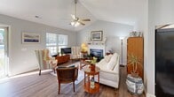 Located at 632 Harkey Rd in Sanford, NC, this well-maintained single-story home offers a thoughtfully designed layout across two bedrooms and two bathrooms. The inviting living room is a standout, featuring soaring vaulted ceilings, a ceiling fan, a classic fireplace with a white mantel, and large windows that flood the space with natural light and views of the surrounding greenery. Hardwood-style flooring flows throughout the home, adding warmth and continuity.

The combined dining room and kitchen area is both functional and welcoming. The dining space benefits from natural light through slatted blinds, while the kitchen impresses with abundant white cabinetry, light countertops, and black appliances, offering generous prep and storage space.

The spacious primary bedroom features vaulted ceilings, a ceiling fan, and large windows overlooking the outdoors, creating a bright and airy retreat. The second bedroom is comfortable and well-proportioned. Both bathrooms are clean and functional, with one featuring a white vanity with ample cabinet storage and elegant lighting.

A connecting hallway links the rooms seamlessly, and the overall aesthetic throughout is neutral and light, with soft gray walls and warm wood-toned floors creating a cohesive, welcoming ambiance.