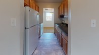 Located at 820 Carvel Dr in Dover, Delaware, this single-floor residence offers a practical and well-organized layout. The galley-style kitchen is efficiently designed with warm wood cabinetry lining both sides, dark granite countertops, a double-basin sink, and wood-look vinyl flooring. A window at the end of the kitchen allows natural light to filter in, and appliances including a refrigerator and range are included.

The living area is generously proportioned, featuring neutral wall-to-wall carpeting and multiple windows that bring in natural light and views of the surrounding neighborhood. The open feel of this space provides flexibility for a variety of furniture arrangements.

The bedrooms continue the carpeted aesthetic and maintain a clean, neutral palette. Each room includes closet storage with louvered or paneled sliding doors, and one bedroom features direct access to the bathroom. The full bathroom is outfitted with a tub-shower combination unit, tile-accented walls with a subtle teal detail, wood-look vinyl flooring, and standard fixtures throughout.

Overall, the space presents a clean, move-in-ready environment with consistent finishes, ample storage, and a straightforward single-level floor plan suited for comfortable everyday living.