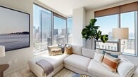 This sophisticated high-rise residence offers 2 bedrooms, 3 bathrooms, and a thoughtfully designed single-floor layout. Floor-to-ceiling windows throughout flood the space with natural light and frame dramatic panoramic views of the city skyline and waterfront beyond.

The open-concept kitchen and living area serves as the heart of the home. The kitchen features sleek, modern cabinetry, stainless steel appliances including a gas range and built-in oven, a large center island with bar seating, and a window overlooking sweeping city and water views. The adjacent living area is anchored by expansive corner windows that maximize the breathtaking urban panorama.

The generously sized primary bedroom enjoys its own floor-to-ceiling window with stunning skyline and waterfront views, and is complemented by a dedicated walk-in closet with custom shelving and hanging systems. The second bedroom is a comfortable, well-appointed space. Both are served by clean, modern bathrooms featuring floating vanities, backlit mirrors, large-format tile flooring, and contemporary fixtures. A third bathroom provides added convenience.

Light hardwood flooring runs throughout, and well-proportioned hallways connect each area seamlessly. The overall ambiance is bright, airy, and distinctly modern.