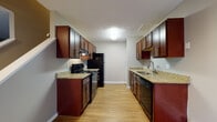 Located at 1112 Ashberry Village Dr. in Columbus, Ohio, this two-story residence offers a well-organized layout designed for comfortable everyday living. A carpeted staircase with white railings connects both levels, providing a clean and functional transition between floors.

The kitchen is a standout feature, designed in a galley configuration with rich, dark cabinetry lining both sides. Granite-style countertops provide ample prep space, while black appliances — including a refrigerator, range, and dishwasher — deliver a cohesive, modern aesthetic. Light hardwood-style flooring runs throughout the kitchen, adding warmth and easy maintenance. A dedicated in-unit laundry area is conveniently located just off the kitchen.

The living areas and bedrooms are finished with plush wall-to-wall carpeting in neutral tones, creating a comfortable and inviting atmosphere. Bedrooms are generously proportioned, featuring ceiling fans, windows with natural light, and wall-unit air conditioning. The neutral gray wall palette throughout the home provides a versatile backdrop.

The bathroom continues the consistent design language, featuring a dark wood vanity with a granite-topped sink, wood-look flooring, and clean, simple fixtures. The overall aesthetic throughout the home is cohesive, functional, and move-in ready.