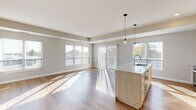 This well-appointed 3-bedroom, 2-bathroom home in Cottage Grove, MN offers a thoughtfully designed single-floor layout with modern finishes throughout. The open-concept living and kitchen area is a standout feature, bathed in natural light streaming through multiple large windows. The kitchen is equipped with stainless steel appliances, including an electric range and over-the-range microwave, light wood cabinetry, a quartz countertop island with pendant lighting and an integrated sink, and a geometric tile backsplash. The living area flows seamlessly from the kitchen, featuring durable wood-style flooring and access to an outdoor area via a sliding glass door. The bedrooms offer plush carpeting and generous natural light, with the primary bedroom providing a comfortable, well-sized retreat. Two closets include a walk-in with wire shelving for ample storage. The two bathrooms are finished with wood-look tile flooring and light wood vanities — one featuring a tub/shower combo and the other a glass-enclosed walk-in shower. A dedicated in-unit laundry space with a stacked washer and dryer adds everyday convenience. Neutral tones and clean lines throughout create a bright, cohesive ambiance.