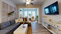 Located at 2451 Margarita Dr in Myrtle Beach, SC, this single-story unit offers a well-designed coastal aesthetic with warm, neutral tones and durable wood-style flooring throughout. The open-concept kitchen is equipped with stainless steel appliances, including a refrigerator, electric range, and over-the-range microwave, complemented by rich dark wood cabinetry, granite-style countertops, and a peninsula with bar seating. A compact dining area sits adjacent to the kitchen, ideal for casual meals. In-unit laundry is also conveniently located nearby. The living room features a ceiling fan and flows seamlessly into a sunlit sitting or flex room with large windows that invite natural light, creating a bright and airy atmosphere. Coastal-themed décor accents tie the spaces together cohesively. The primary bedroom is a comfortable retreat with a ceiling fan, natural light from a window, and ample closet space. A second bedroom also offers a walk-in closet, providing generous storage. The bathroom includes a vanity with granite-style countertops, dark wood cabinetry, and a tub-shower combination. Throughout the unit, the consistent use of light wall colors and wood-style flooring creates a clean, unified look suited to coastal living.