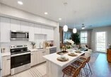 Located at 3065 Champion Ring Rd in Fort Myers, FL, this thoughtfully designed 2-bedroom, 3-bathroom residence offers a modern aesthetic throughout its efficiently planned single-floor layout. The open-concept kitchen and living area serves as the heart of the home, featuring a contemporary kitchen with sleek two-tone cabinetry — crisp white uppers paired with warm wood-tone lower cabinets — quartz countertops, a white subway tile backsplash, stainless steel appliances, and a peninsula with seating for casual dining. Pendant lighting adds a refined touch overhead. The adjoining living room is warm and inviting, anchored by a bold accent wall and natural light streaming through large windows. Light-toned wood-style flooring flows throughout, enhancing the airy ambiance. The spacious primary bedroom features an accent wall, generous natural light, and ample closet space. The second bedroom is well-proportioned and equally bright. Three well-appointed bathrooms include quartz vanity countertops, wood-tone cabinetry, and clean tile work — one featuring a soaking tub and shower combination. A hallway and two closets provide practical storage solutions, completing this polished and functional Fort Myers residence.