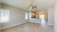 Located at 24 Winnow Way in Wilmington, NC, this well-designed single-story home offers a comfortable and functional layout across three bedrooms and three full bathrooms. The open-concept living area flows seamlessly into a combined kitchen and dining space, where light-toned luxury vinyl plank flooring, neutral walls, and ceiling fans create a bright, airy atmosphere. The kitchen is outfitted with white cabinetry, granite countertops, stainless steel appliances including a refrigerator and range, a center island with additional counter space, and recessed lighting. A pendant chandelier illuminates the adjacent dining area, which features plantation shutters and views toward the backyard. The spacious primary bedroom includes a tray ceiling, ceiling fan, plush carpet, multiple windows, and direct access to a walk-in closet with generous shelving and hanging space. Additional bedrooms are well-sized, with LVP flooring and ample natural light from surrounding windows. The bathrooms are cleanly appointed, and a dedicated laundry room houses a full-size washer and dryer. Built-in shelving accents the living area, and the home also includes an attached garage with automatic door opener. The layout is efficient and cohesive throughout.