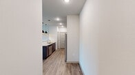This single-floor, 2-bedroom, 2-bathroom residence is designed with a clean, modern aesthetic and a practical layout that maximizes everyday comfort. The open-concept kitchen and living area serves as the heart of the home, featuring rich dark cabinetry, granite-style countertops, stainless steel appliances including a refrigerator, range, microwave, and dishwasher, and warm wood-look flooring throughout. Stylish pendant lighting adds a contemporary touch above the kitchen sink area. The living room is bright and inviting, highlighted by a graceful arched doorway, a ceiling fan, and multiple windows that usher in natural light and outdoor views. The two bedrooms offer a calm retreat, with plush carpeting, neutral walls, and easy access to dedicated closets with built-in shelving. Each bathroom is finished with tile flooring and tiled shower surrounds, providing a clean and polished look. A dedicated laundry area with in-unit washer and dryer adds everyday convenience. Throughout the residence, recessed lighting, crisp white walls, and cohesive finishes create a bright, move-in-ready atmosphere that is both functional and welcoming.
