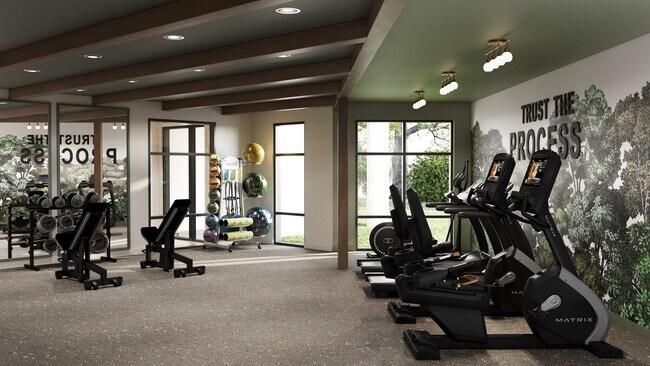Gimnasio moderno con cintas de correr, pesas libres, equipo de entrenamiento y una pared con un cartel motivacional que dice "Confía en el proceso". - Oakwood Trails