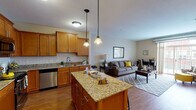 Located at 20 Sixth St NW in Osseo, Minnesota, this single-floor residence offers a thoughtfully designed open-concept layout that seamlessly connects the kitchen, dining, and living areas. The kitchen is a standout feature, boasting warm honey-toned cabinetry, granite countertops with subtle veining, a classic white subway tile backsplash, and a full suite of stainless steel appliances including a refrigerator, range, microwave, and dishwasher. A central granite-topped island provides additional prep space and casual seating. Pendant lighting above the island complements the overall warm ambiance of the space. The living area flows naturally from the kitchen, featuring rich hardwood-style flooring, neutral-toned walls, and generous natural light from a large sliding door. The bedroom offers plush carpeting, a bright window with views to the exterior, and ample closet space. The full bathroom mirrors the quality found throughout the unit, with granite vanity countertops, warm wood cabinetry, hardwood-style flooring, and a glass-enclosed shower and tub combination. Consistent finishes and a cohesive design palette create a comfortable and functional living environment throughout this Osseo residence.