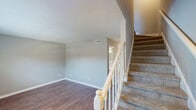 Located at 2920 Chapel Hill Rd in Durham, NC, this two-story, 2-bedroom, 2-bathroom home offers a practical and comfortable layout spread across two floors. The main level features a combined kitchen and living room area alongside a utility room. The kitchen is well-appointed with white cabinetry, dark countertops, and a full suite of stainless steel appliances, including a refrigerator, electric range with microwave, and dishwasher, all complemented by warm hardwood-style flooring. The living room is open and bright, with natural light streaming through windows and the same wood-style flooring continuing throughout. A second room on the main floor, also with hardwood-style floors, offers flexible use as a dining area or additional living space. Upstairs, two carpeted bedrooms each feature ceiling fans with light fixtures and windows that bring in natural light. The spacious primary bedroom includes two closets, providing ample storage. Both bathrooms are finished in neutral tones, with one featuring a tub/shower combination, wood-style floors, and a vanity with white countertops. Textured ceilings and neutral gray walls are consistent throughout, giving the home a clean, cohesive aesthetic.