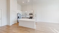 Located at 215 Florida St in Knoxville, TN, this thoughtfully designed one-bedroom, one-bathroom residence offers a bright and modern living experience across a single, well-organized floor. Soaring ceilings define the open-concept kitchen and living area, creating an expansive, airy atmosphere filled with natural light streaming through large windows and French doors. The kitchen is a standout feature, showcasing white shaker cabinetry with matte black hardware, gleaming quartz countertops, a generous center island with pendant lighting overhead, and a full suite of stainless steel appliances including a refrigerator with ice maker, range, microwave, and dishwasher. A dedicated pantry provides additional storage. Light-toned hardwood flooring flows seamlessly throughout the entire space, enhancing the clean, contemporary aesthetic. The spacious primary bedroom benefits from tall windows that invite abundant natural light and urban views. The bathroom is well-appointed with quartz countertops, a vanity with ample storage, and a glass-enclosed shower, with direct access to a walk-in closet featuring built-in shelving. Additional conveniences include an in-unit laundry area. The private balcony overlooks the surrounding community courtyard, offering a pleasant outdoor retreat. The overall ambiance is fresh, modern, and move-in ready.