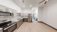 Located at 627 E Emma Ave in Springdale, Arkansas, this thoughtfully designed one-bedroom, one-bathroom unit offers a clean, modern aesthetic across a single floor. Light wood-look flooring flows consistently throughout every room, complementing the bright white walls and creating a cohesive, contemporary feel.

The combined kitchen and living area serves as the heart of the unit. The kitchen is well-appointed with stainless steel appliances — including a refrigerator, electric range, and over-the-range microwave — paired with two-tone cabinetry featuring light upper cabinets and darker lower cabinets. Stone-look countertops and a classic white subway tile backsplash complete the polished look. Tall ceilings lend an open, airy quality to the space.

The bedroom is a quiet, comfortable retreat filled with natural light from a large window fitted with horizontal blinds. The room includes a spacious closet with sliding doors, offering ample storage. A dedicated laundry area with a stacked washer and dryer unit is conveniently accessible from the bedroom.

The bathroom features a granite-topped vanity with dark cabinetry, a toilet, and a bathtub with a shower, all finished in a clean, neutral palette consistent with the rest of the unit. A utility room and hallway round out the functional layout, making efficient use of every square foot.