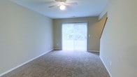 Located at 2591 Venturi House in Columbus, Ohio, this two-story home offers a practical and comfortable layout designed for everyday living. The main living area features wall-to-wall carpeting that adds warmth underfoot, complemented by neutral-toned walls that create a clean, versatile backdrop for any décor style. A ceiling fan with integrated lighting provides both air circulation and ambient illumination, contributing to a comfortable atmosphere throughout the seasons. A prominent sliding glass door floods the room with natural light and offers views of the surrounding greenery, creating a bright and airy feel. Vertical blinds on the sliding door allow for adjustable light control and privacy. The staircase, visible from the living space, connects the two floors and hints at additional living or sleeping quarters above. The overall ambiance of the home is understated and functional, with a neutral palette that makes spaces feel open and easy to personalize. Its Columbus location places it within reach of local amenities, making it a well-situated option for those seeking a multi-level home in the area.
