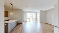 This well-appointed two-bedroom, two-bathroom residence in Chicago's 60618 neighborhood offers a thoughtfully designed single-level layout with generous overall square footage. The open-concept living and dining area serves as the heart of the home, featuring warm hardwood-style flooring throughout and a wall of large floor-to-ceiling glass doors that flood the space with natural light and provide views of the surrounding cityscape.

The kitchen is a standout feature, showcasing flat-front wood-toned cabinetry, a striking quartz waterfall island illuminated by geometric pendant lighting, white subway tile backsplash, and a full suite of stainless steel appliances including a gas range and French door refrigerator.

The spacious primary bedroom provides ample room and benefits from its own large window with city views. The primary bathroom offers a double floating vanity with modern chrome fixtures, a wide wall mirror, and an oversized glass-enclosed shower clad in marble-style tile. The secondary bathroom features full-height textured tile surround and a soaking tub. Additional highlights include a dedicated closet and hallway connecting the private and common areas seamlessly.