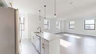 Located at 758 North Broadway in Milwaukee's vibrant 53202 zip code, this thoughtfully designed 2-bedroom, 2-bathroom residence offers a clean, modern aesthetic throughout. The open-concept kitchen and living area serves as the heart of the home, anchored by a central island with white quartz countertops, white cabinetry with gold hardware, a black matte faucet, and stainless steel appliances. Sleek pendant lights hang above the island, adding a contemporary touch. Multiple black-framed windows flood the living space with natural light and offer views of the surrounding cityscape.

Both bedrooms are carpeted and finished in crisp white, with the primary bedroom featuring multiple windows and ample square footage. The second bedroom includes a double-door closet for convenient storage. Two closets are distributed throughout the unit.

The bathrooms are finished with classic black-and-white hexagonal tile flooring and white subway tile. One bathroom features a soaking tub, while the other offers a glass-enclosed walk-in shower with a built-in niche, white vanity, and black hardware accents. A dedicated laundry area and two hallways complete the functional layout, making this a well-appointed urban residence.