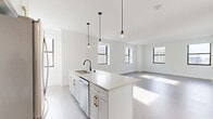 Located at 758 North Broadway in Milwaukee's vibrant 53202 zip code, this thoughtfully designed 2-bedroom, 2-bathroom residence offers a clean, modern aesthetic throughout. The open-concept kitchen and living area serves as the heart of the home, anchored by a central island with white quartz countertops, white cabinetry with gold hardware, a black matte faucet, and stainless steel appliances. Sleek pendant lights hang above the island, adding a contemporary touch. Multiple black-framed windows flood the living space with natural light and offer views of the surrounding cityscape.

Both bedrooms are carpeted and finished in crisp white, with the primary bedroom featuring multiple windows and ample square footage. The second bedroom includes a double-door closet for convenient storage. Two closets are distributed throughout the unit.

The bathrooms are finished with classic black-and-white hexagonal tile flooring and white subway tile. One bathroom features a soaking tub, while the other offers a glass-enclosed walk-in shower with a built-in niche, white vanity, and black hardware accents. A dedicated laundry area and two hallways complete the functional layout, making this a well-appointed urban residence.