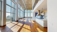 Located in Houston's vibrant Montrose neighborhood, this two-story residence offers an impressive blend of industrial-modern architecture and open, light-filled living. The main floor commands attention with its dramatic double-height ceilings clad in exposed concrete, an expansive wall of floor-to-ceiling grid windows that flood the space with natural light, and rich hardwood flooring throughout. Track lighting runs across the ceilings, adding a contemporary, loft-inspired aesthetic. The open-concept living area flows seamlessly into the kitchen, which features a sleek island, stone countertops, and a statement stainless steel range hood. Two living areas provide flexible gathering and entertaining space. The upper floor houses the generously proportioned primary suite — an exceptionally spacious retreat with large windows framing panoramic views of the Houston skyline. Walk-in closets with built-in wire shelving systems offer ample storage. Three additional closets and a dedicated laundry room with full-size washer and dryer add practicality. Four bathrooms, including one featuring a bidet, are finished with stone tile flooring. Secondary bedrooms are carpeted and well-sized. An interior balcony overlooks the dramatic main living space below, completing this architecturally distinctive urban residence.