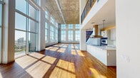 Located in Houston's vibrant Montrose neighborhood, this two-story residence offers an impressive blend of industrial-modern architecture and open, light-filled living. The main floor commands attention with its dramatic double-height ceilings clad in exposed concrete, an expansive wall of floor-to-ceiling grid windows that flood the space with natural light, and rich hardwood flooring throughout. Track lighting runs across the ceilings, adding a contemporary, loft-inspired aesthetic. The open-concept living area flows seamlessly into the kitchen, which features a sleek island, stone countertops, and a statement stainless steel range hood. Two living areas provide flexible gathering and entertaining space. The upper floor houses the generously proportioned primary suite — an exceptionally spacious retreat with large windows framing panoramic views of the Houston skyline. Walk-in closets with built-in wire shelving systems offer ample storage. Three additional closets and a dedicated laundry room with full-size washer and dryer add practicality. Four bathrooms, including one featuring a bidet, are finished with stone tile flooring. Secondary bedrooms are carpeted and well-sized. An interior balcony overlooks the dramatic main living space below, completing this architecturally distinctive urban residence.
