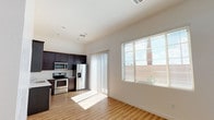 Located at 940 East Hampton Ave in Mesa, Arizona, this single-floor unit offers a clean, modern interior designed for comfortable everyday living. The open-concept layout connects the kitchen and living area seamlessly, creating a bright and functional shared space. Large windows and a sliding glass door flood the area with natural light, enhancing the airy feel of the space.

The kitchen is well-appointed with rich dark-stained cabinetry extending to the upper walls, light-toned countertops, a double-basin sink, and a full suite of stainless steel appliances including a refrigerator with ice maker, electric range, built-in microwave, and dishwasher. Ample cabinet storage and generous counter space make the kitchen both practical and visually appealing.

Light wood-look flooring runs consistently throughout the unit, contributing to a cohesive and contemporary aesthetic. The bedrooms are bright and simply finished, each featuring a window that invites natural light and overhead ventilation for climate control. Closet access is conveniently located in the hallway area.

The bathroom features a dark wood-toned vanity with a white countertop, a chrome towel ring, a toilet, and a small window for ventilation and natural light. White walls and clean finishes throughout the unit create a neutral, move-in-ready environment well-suited to a variety of living arrangements.