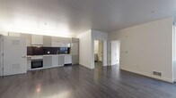 Located at 3015 San Pablo Ave in Berkeley, California, this single-floor unit offers a clean, contemporary design with thoughtful finishes throughout. Dark hardwood flooring runs continuously across the open-concept living and dining area, creating a cohesive and polished aesthetic. Large windows invite abundant natural light into the main living space, providing views of the surrounding neighborhood.

The modern kitchen is well-appointed with sleek gray cabinetry, a dark tile backsplash, light countertops, a gas cooktop, built-in oven, and a stainless steel sink. A dedicated in-unit laundry closet with a stacked washer and dryer is conveniently accessible just off the kitchen area.

The bedroom is bright and generously proportioned, featuring a large window that brings in natural light and outdoor views. A spacious walk-in closet with wire shelving provides ample storage. The bathroom is finished in a clean, contemporary style with white subway tile surrounding the full bathtub and shower, a large vanity mirror, white cabinetry with drawers, and dark mosaic floor tile. The overall design of the unit emphasizes modern minimalism, with white walls, clean lines, and functional spaces throughout.