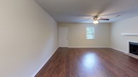 This single-story home offers a practical and well-organized layout across several distinct living spaces. The main living area makes a strong first impression with rich, dark hardwood-style flooring, neutral beige walls, a textured ceiling, and a ceiling fan with integrated lighting. A window allows natural light to filter in, complementing the entry door nearby. The galley-style kitchen is efficiently designed with white cabinetry, laminate countertops, dark hardwood-style flooring, and stainless steel appliances including a refrigerator and dishwasher. Adjacent to the kitchen, a dining or flex room features the same warm hardwood-style flooring, a chandelier overhead, and a closet with bi-fold doors. The primary bedroom is carpeted and generously sized, equipped with a ceiling fan, a wide sliding-door closet, and direct access to the full bathroom. Additional bedrooms are also carpeted with textured ceilings and neutral walls, offering versatile use as sleeping quarters or office space. The full bathroom is appointed with a tub-shower combination, toilet, hardwood-style flooring, and an overhead storage cabinet, providing functional utility. Throughout, consistent neutral tones and practical finishes create a cohesive and move-in-ready living environment.
