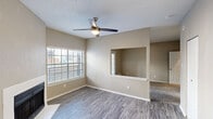 Located at 5912 Northwest Dr in Mesquite, TX, this single-floor, one-bedroom, one-bathroom residence offers a thoughtfully arranged layout across a compact yet functional footprint. The living area is finished with wood-look plank flooring and features a white-surround fireplace as a focal point, flanked by a large window fitted with horizontal blinds that invite generous natural light. A ceiling fan with integrated lighting overhead provides both comfort and illumination. A distinctive pass-through architectural opening connects the living space to the adjacent area, adding visual depth and an open feel. The bedroom is carpeted and generously sized, with neutral warm-toned walls and a dedicated closet with built-in shelving for organized storage. The bathroom is straightforward in design, equipped with a tub-shower combination finished in white tile, a vanity with a light countertop, and a brushed nickel towel bar. Textured ceilings are present throughout the unit, consistent with the overall style of the home. Neutral greige wall tones carry throughout every room, creating a cohesive, understated aesthetic. The space also includes a front entry door with sidelights and patio-style French doors, offering additional access and natural light to the main living area.