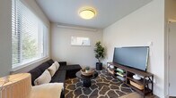 Located at 2011 NE 112th Ave in Vancouver, Washington, this single-floor unit offers a thoughtfully designed layout with a cohesive, modern aesthetic throughout. Light wood-tone flooring flows continuously across all rooms, creating a sense of unity and warmth.

The kitchen is a functional centerpiece, featuring white shaker-style cabinetry, gray countertops, a tile backsplash, and a full suite of stainless steel appliances including a refrigerator, range, microwave, and dishwasher. A peninsula with bar seating connects the kitchen to a dedicated dining area, making the space well-suited for both casual meals and entertaining.

The living room is a comfortable, well-lit retreat with multiple windows admitting natural light and a wall-mounted mini-split system for climate control. Clean white walls and neutral tones give the space a calm, open feel.

The bedroom is generously proportioned, featuring dual windows that frame views of the surrounding neighborhood, a ceiling fan, and ample space for a full furniture arrangement. A hallway with closet access leads to the bathroom, which offers white cabinetry, dark countertops, and a large vanity mirror with overhead lighting. The overall design is clean, modern, and move-in ready.