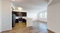 Located in San Ramon, CA, this single-floor residence offers a thoughtfully designed open-concept layout that seamlessly connects the kitchen, dining, and living areas. The kitchen is a standout feature, equipped with rich dark-espresso cabinetry, white quartz countertops, a central peninsula, and a full suite of stainless steel Whirlpool appliances — including a gas range, over-the-range microwave, and french door refrigerator. Wood-look plank flooring flows throughout the main living areas, adding warmth and visual continuity to the bright, white-walled interior. Natural light enters through multiple windows, enhancing the open and airy feel of the space. The bedroom features plush carpeting and offers access to a well-appointed bathroom, complete with dark cabinetry, white countertops, a sink vanity with mirror, and a full bathtub and shower combination. The overall design aesthetic is clean and contemporary, with a neutral color palette that provides a versatile backdrop for a variety of interior styles. The layout maximizes functionality while maintaining an open, comfortable living environment suited for everyday living in the San Ramon community.