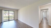 This single-floor, 3-bedroom, 2-bathroom home offers a clean and modern living environment with a thoughtful layout. Throughout the space, durable wood-look flooring and crisp white walls create a bright, cohesive aesthetic complemented by textured ceilings.

The living room is a comfortable and open space anchored by a sliding glass door that leads to a private balcony, inviting natural light and outdoor views. The galley-style kitchen is well-equipped with stainless steel appliances including a gas range, microwave, refrigerator, and dishwasher. Grey shaker-style cabinetry and granite-look countertops provide ample storage and workspace, while a skylight enhances the sense of brightness.

The primary bedroom is generously sized and connects to the layout via hallways that also serve two additional bedrooms, each featuring windows that bring in natural light. Two dedicated closets provide convenient storage throughout.

Both bathrooms are finished with granite-topped vanities and grey cabinetry consistent with the kitchen's design. One bathroom features a full tub-shower combination with floor-to-ceiling stone-look tile surround, adding a refined touch. The home's neutral palette and updated finishes make it a move-in ready space suitable for a variety of lifestyles.