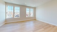 Located at 775 Morton St E in Boston's Mattapan neighborhood, this thoughtfully designed single-floor unit offers a clean, contemporary aesthetic throughout. Light hardwood flooring runs continuously across the living and bedroom areas, reflecting natural light and contributing to an airy, open ambiance.

The kitchen is a standout feature, showcasing white shaker cabinetry with brass hardware, sleek white quartz countertops, and a large island with an undermount sink and gold-toned faucet. Stainless steel appliances — including a French door refrigerator, electric range, built-in microwave, and dishwasher — complete the modern setup. Louvered double doors provide convenient pantry or utility storage.

The living area is bathed in natural light from large double-hung windows that frame views of the surrounding Boston neighborhood. Recessed lighting throughout ensures bright, even illumination at all times of day.

The bedroom features a set of classic double doors opening to a spacious closet, complemented by generous windows that invite additional natural light.

The bathroom is finished with marble-look tile flooring and a full tub-shower combination equipped with brushed nickel grab bars, reflecting a design that prioritizes both style and accessibility. The overall palette of neutral whites and soft beiges lends a cohesive, move-in-ready feel to the entire space.