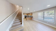 Located at 711 W 32nd St in Austin, TX, this two-story residence offers a thoughtfully organized layout across two floors. The main level houses the kitchen and primary living area, while the upper level is dedicated to the bedroom and bathrooms. Light wood-tone flooring flows consistently throughout both floors, creating a cohesive and clean aesthetic.

The kitchen is a functional highlight of the main floor, featuring warm honey-toned wood cabinetry, dark stone-look countertops, a peninsula with seating potential, pendant lighting, recessed ceiling lights, and stainless steel appliances including a refrigerator and microwave. A dishwasher is integrated beneath the counter, maximizing utility in the space.

The bedroom occupies a generous portion of the upper floor and is filled with natural light from multiple windows fitted with horizontal blinds. A ceiling fan adds comfort, and the room connects directly to a walk-in closet equipped with a hanging rod and built-in shelving for organized storage.

The primary bathroom features warm wood cabinetry with dark countertops, a single vanity sink, a large mirror, and a soaking tub with tile surround. A window brings in natural light. A second bathroom provides additional convenience for guests or daily use. In-unit laundry rounds out the practical amenities of this well-appointed Austin residence.