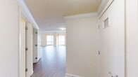 This thoughtfully designed 2-bedroom, 2-bathroom residence offers a spacious and functional layout spread across a single floor. The open-concept living room is a standout feature, showcasing gleaming hardwood-style flooring, elegant crown molding, and large windows that frame impressive city skyline views, flooding the space with natural light. The kitchen is equipped with light wood cabinetry, stone countertops, stainless steel appliances, and a convenient pantry with wire shelving for ample storage.

The primary bedroom is generously proportioned, featuring plush carpeting, a large window with city views, and a walk-in closet outfitted with built-in wire shelving and hanging rods. The second bedroom is equally well-sized with soft carpeting and easy access to the hallway. Both bathrooms are cleanly finished, with one featuring marble-look tile flooring, a combined tub and shower with white tile surround, and a wood-toned vanity with mirror.

Throughout the residence, warm cream-toned walls create a bright and neutral palette. The entryway hallway, finished with hardwood-style flooring and crown molding, provides a welcoming transition into the expansive main living area. This residence combines practical storage solutions, refined architectural details, and sweeping urban views for a comfortable city living experience.